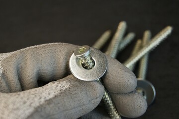 Assembler's work process. New mounting screw with steel washers in the hand of the assembler.