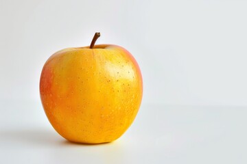 Ripe, yellow and red apple with stem is standing on a plain white background