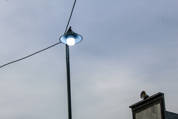 Selective focus street lights connected by cables with blue sky background in the park during the day