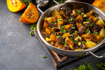 Warm pumpkin stew with potato and beef meat, comfort autumn dinner balanced food, with ingredients on kitchen table