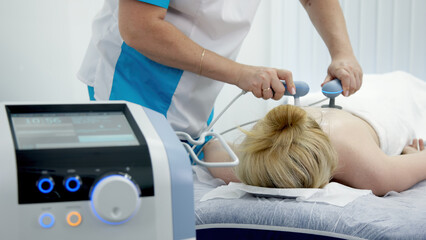 Physiotherapist using TR-THERAPY medical equipment for effective pain relief. Ideal for showcasing advanced treatment methods and modern physiotherapy techniques.