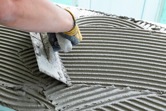 Construction worker bricklayer applies adhesive mortar with trowel on xps (Extruded Polystyrene) board during interior thermal and sound insulation project.