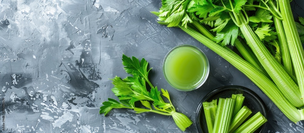 Poster top view of appetizing celery juice and fresh stalks on a gray tabletop, designed as a banner with a