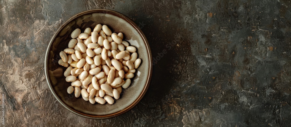 Poster top view of a plate with raw white beans on a table with a copy space image