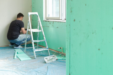 Indoor thermal insulation materials mounted on the wall of a room close-up selective focus. Out of focus insulation specialist installing XPS (Extruded Polystyrene) boards on the wall.