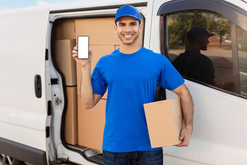 Smiling courier man showing cellphone with white blank screen and holding cardboard box, advertising app for delivery service, mockup