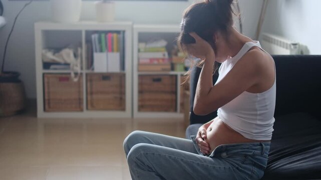 Pregnant woman feeling morning sickness and hormonal discomfort, holding her head in pain. Highlights first-trimester pregnancy symptoms and reproductive health challenges