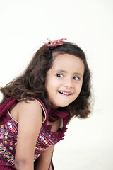  A delightful little girl with sparkling eyes, breaking into a wide, infectious smile. Her expression radiates pure happiness and innocence.