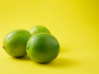 Close up, lime, tropical citrus fruit on yellow background and copy space.