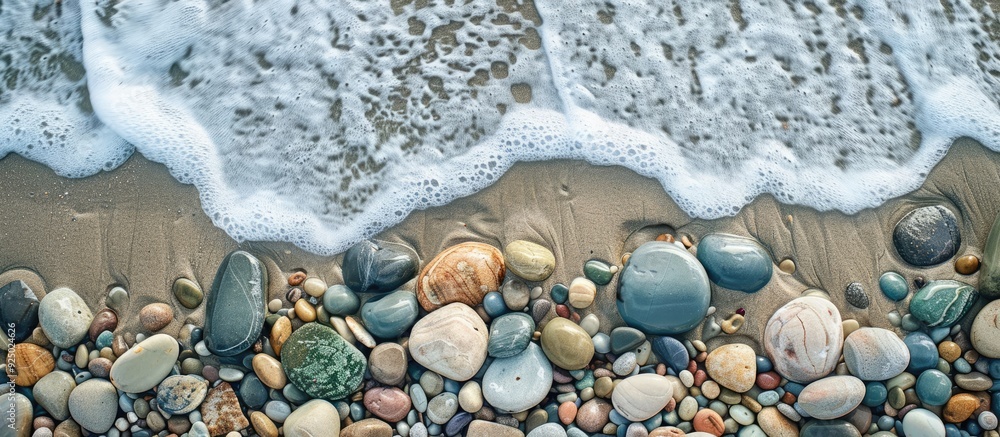 Poster Top view of stones on the beach with ocean waves, providing a textured backdrop for a copy space image.