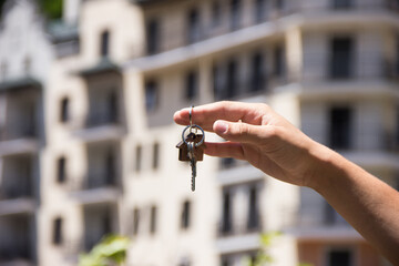 Apartment keys in hand close-up against the background of houses