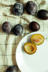 Plums on a white plate on a check kitchen towel, vintage style