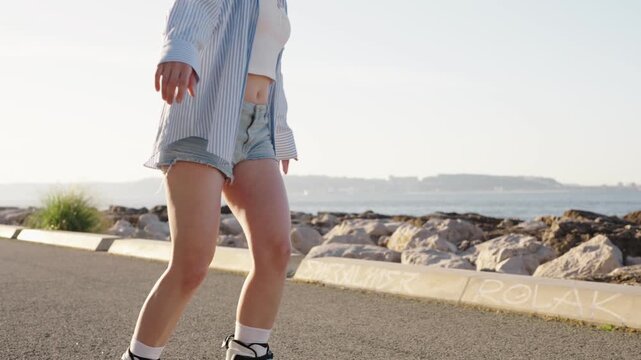An attractive young woman roller skating on a paved waterfront path at sunrise, embodying a sense of freedom and carefree joy.