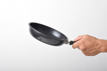 Hand holding Black frying pan with a non-stick coating isolated on white background