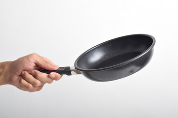 Hand holding Black frying pan with a non-stick coating isolated on white background