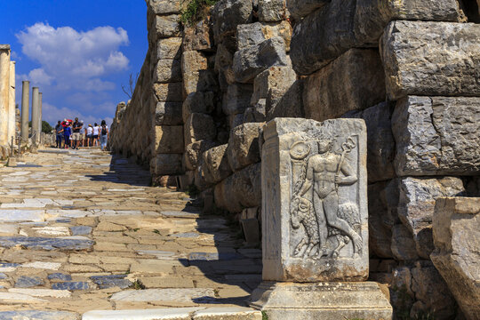 Ephesus, Turkey - June 15, 2022: Summer view of tourists and sculpture of Jason and sheep on stone pillar at historic sites