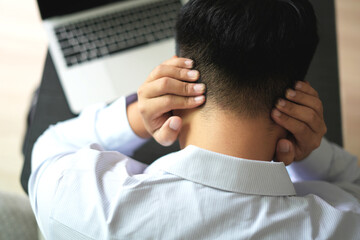 Young asian business man massaging rubbing stiff sore neck and headache tensed muscles fatigued...
