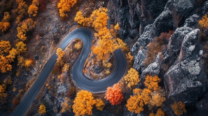 Aerial View of Winding Mountain Road Amidst Vibrant Fall Foliage and Majestic Rocks