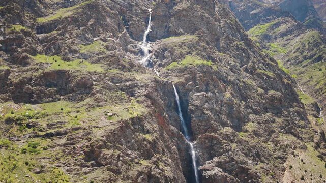 4K shot of waterfall falling from the cliff on the Himalayan mountain peak as seen from Tandi in Lahaul, Himachal Pradesh, India. Waterfall in the Himalayas background with copy space.