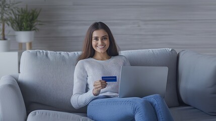 Obraz premium Indian woman holding a credit card while using a laptop, making a retail payment, engaging in online shopping, digital transaction