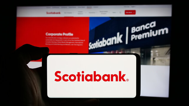 Stuttgart, Germany - 08-12-2024: Person holding cellphone with logo of financial company Bank of Nova Scotia (Scotiabank) in front of business webpage. Focus on phone display.