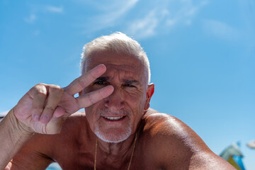 a middle aged man with white hair and goatee happy and smiling taking a selfie on summer vacation