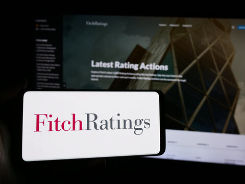 Stuttgart, Germany - 08-13-2024: Person holding smartphone with logo of US credit rating agency Fitch Ratings Inc. in front of website. Focus on phone display.