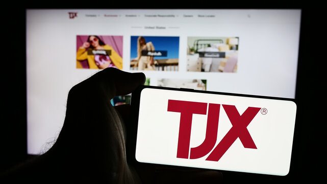 Stuttgart, Germany - 08-13-2024: Person holding smartphone with logo of US department store company The TJX Companies Inc. in front of website. Focus on phone display.