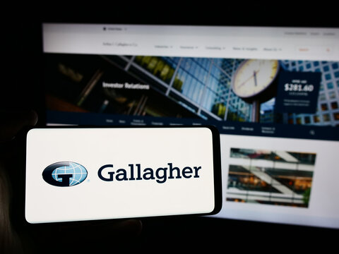 Stuttgart, Germany - 08-13-2024: Person holding smartphone with logo of US insurance company Arthur J. Gallagher Co. (AJG) in front of website. Focus on phone display.