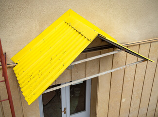 Canopy made of corrugated sheet metal over the basement entrance door