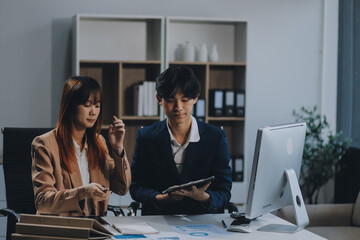 Entrepreneur Asian businessman and businesswoman discussing new business project in tablet in modern Meeting In Modern Office, Asian business casual concept.