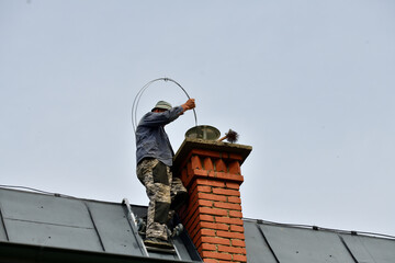 Traditional manual method of cleaning the chimney on the roof