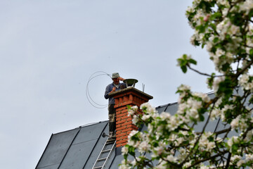 Traditional manual method of cleaning the chimney on the roof
