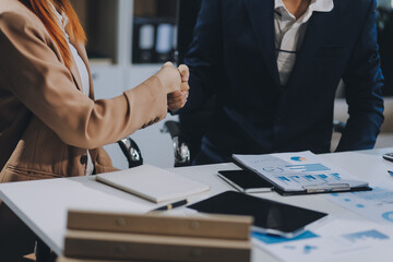 Entrepreneur Asian businessman and businesswoman discussing new business project in tablet in modern Meeting In Modern Office, Asian business casual concept.