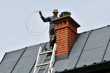 Traditional manual method of cleaning the chimney on the roof