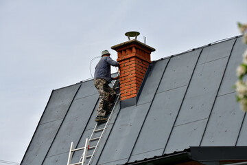 
The roof roofer climbs up the ladder to the roof of the house to fix sheet metal roof
