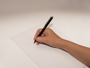 hand with pen writing on a white paper