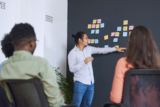 Man, sticky notes and chalk board in office for training, teaching and learning for skill or career development. People, employees and mentor or leader at workshop for internship program and coaching