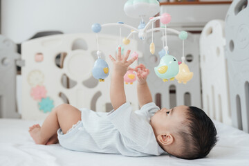 Adorable Asian Baby Boy, 5 Months Old, Smiling and Enjoy Playing with Crib Mobile in Home Playpen.