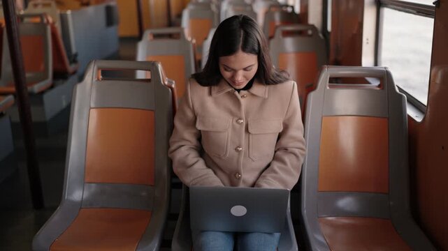A young professional engages in remote work on her laptop while traveling on a ferryboat, showcasing the flexibility of modern work environments.