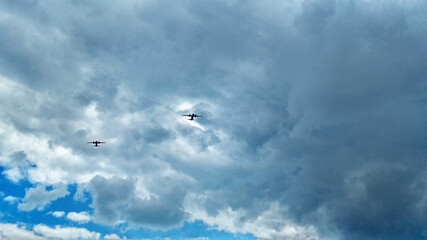 Two military aircraft fly in a cloudy sky during an exercise