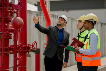 Building inspector man checking fire hose cabinet. engineer and worker in green vest, ear muffs and safety helmet working for building maintenance inspection