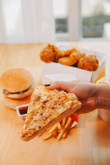 Cropped image of woman holding pizza slice at restaurant