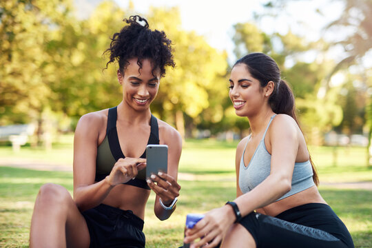 App, fitness and phone with woman friends outdoor in park together for workout routine. Exercise, social media and tracking progress with athlete people on lawn for challenge, performance or training