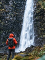 Obraz premium Hiker Standing in Awe of a Majestic Waterfall