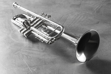 Shiny trumpet on grey textured table. Wind musical instrument