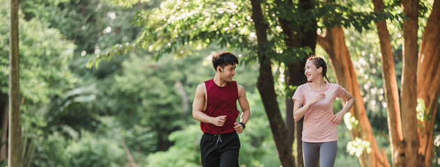 Banner Active two Asian young man and woman in sportswear jogging exercise in park outdoor. Together young couple running outdoor in the morning. Healthy exercise concept.