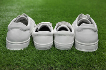 Big and small shoes on green grass