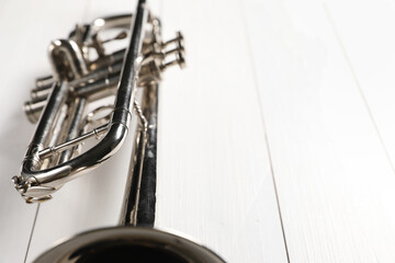 Obraz premium One trumpet on white wooden table, closeup. Space for text