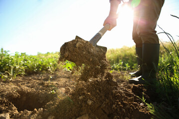 Fototapeta premium Farmer digging soil with shovel on sunny day, closeup
